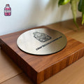 Round engraved metal disc resting on a wooden display block
