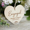 Heart-shaped wooden hanging ornament engraved with engagement details