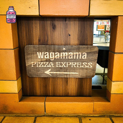 Engraved wooden restaurant direction sign with arrow displayed in a window